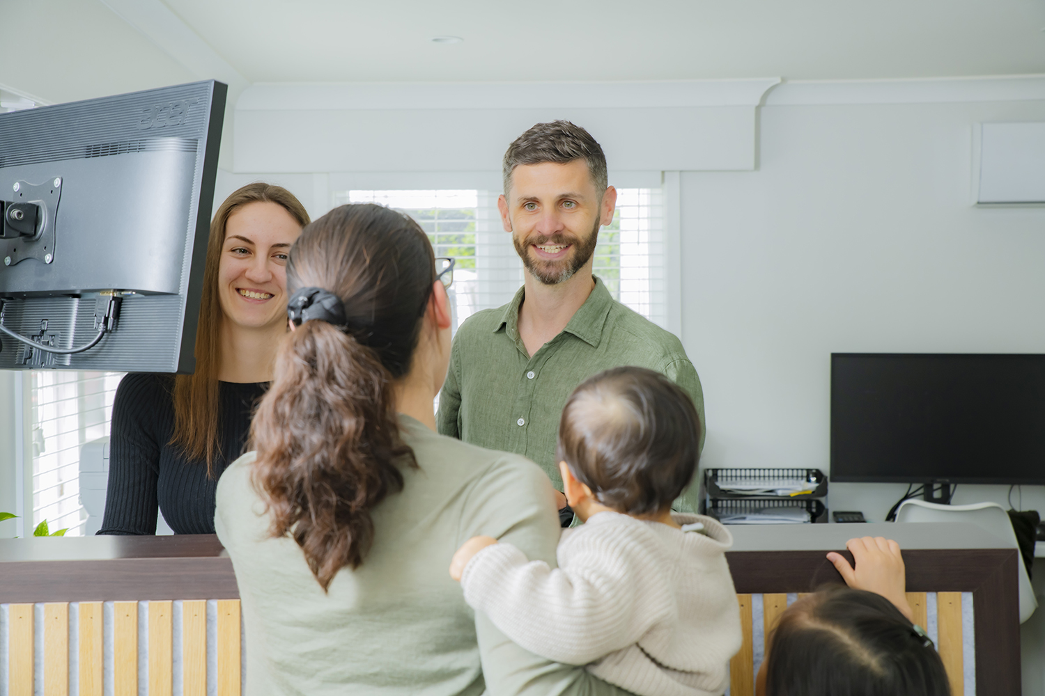 Chiropractic team greeting family at clinic concierge